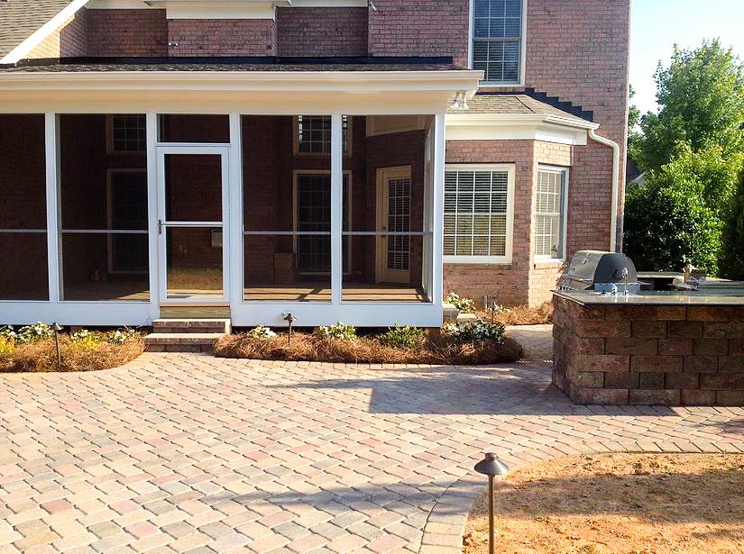 A brick patio with a fire pit and grill.