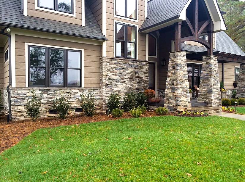 A house with a lawn and stone wall.