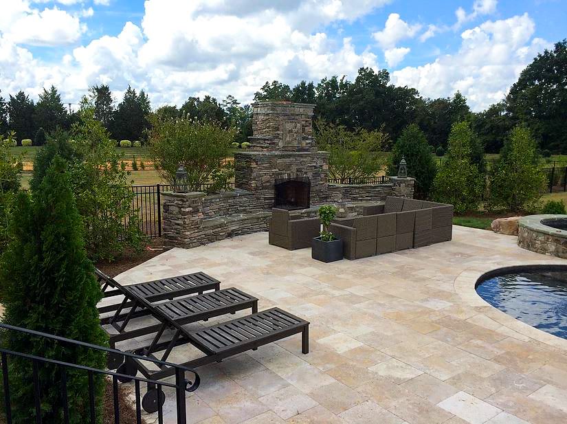 Stone patio with fireplace and pool.