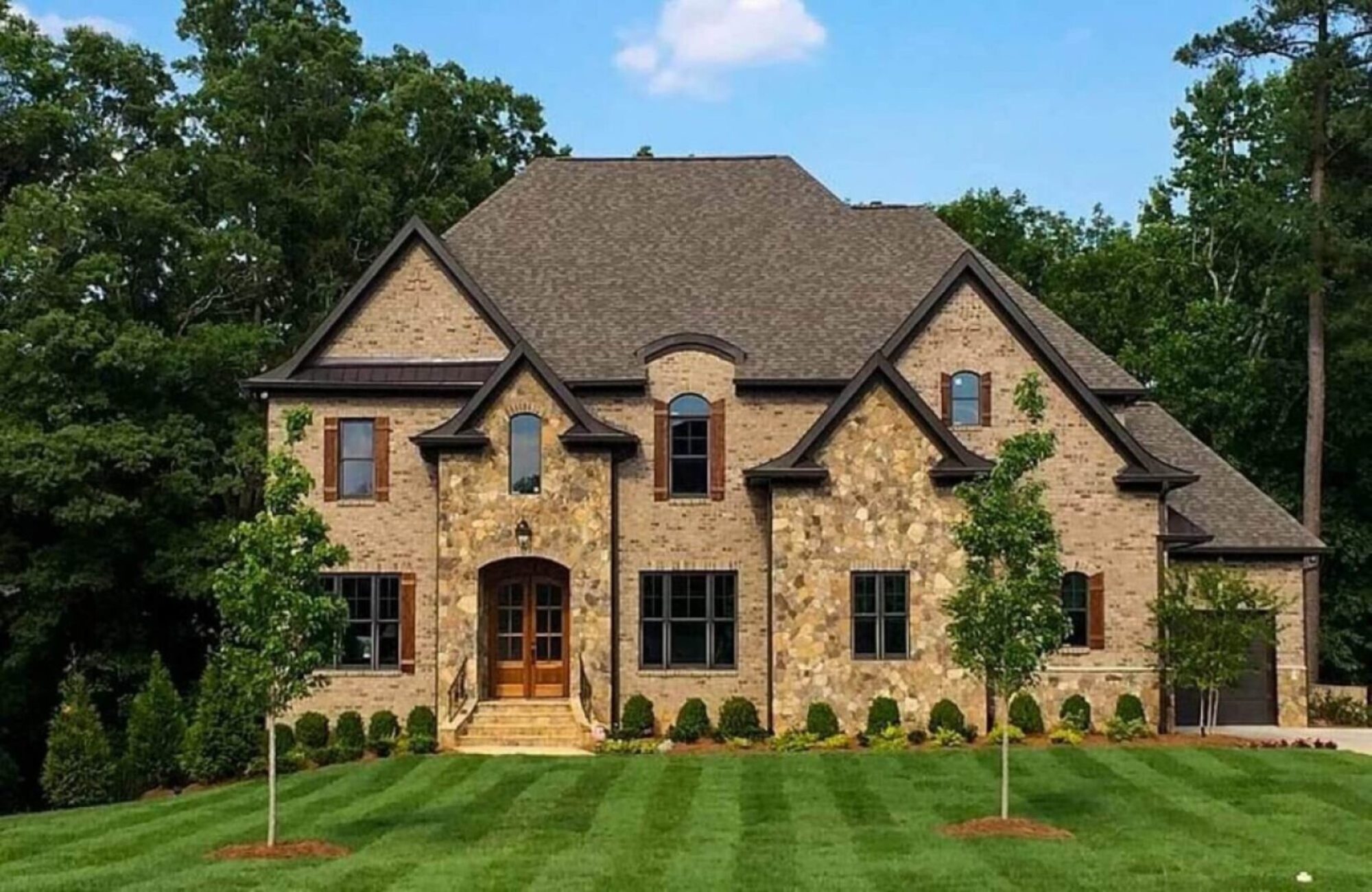 Brick house with a brown roof and lawn.